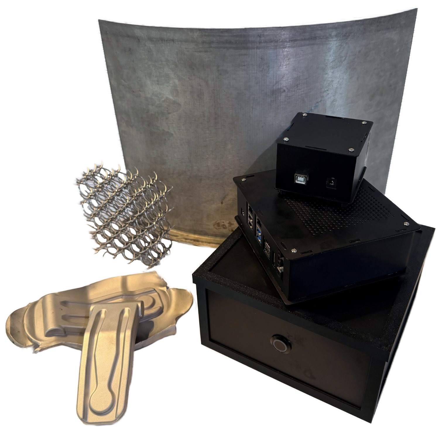 Auf weißem Hintergrund sind die im Projekt entstandenen Demonstratoren zu sehen: Hinten steht eine große, leicht gebogene Metalltafel als warmumgeformtes Teil eines Hovercraft-Propellerschutzes. Links vorne liegt ein warmgepresstes Bauteil einer Containertür, daneben eine feine Gitterstruktur. Rechts sind drei übereinandergestapelte Gehäuse für Elektronikkomponenten (Computer, Steuermodul) zu sehen.